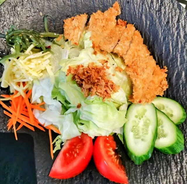 Crispy chicken salad with lettuce, carrots, cucumber, wakame